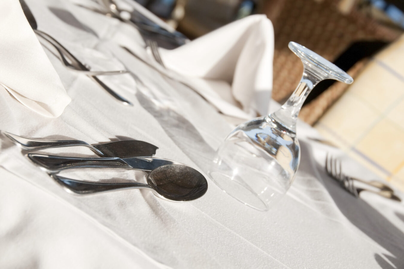 773135 Bugaderia Garraf - Barcelona Noticias 24h Formal dining table setting with silverware laid out and an inverted wine glass on a white cloth tablecloth.